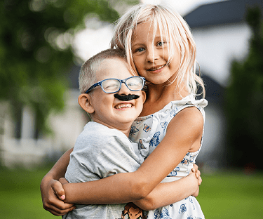 Young brother and sister hugging each other with smiles
