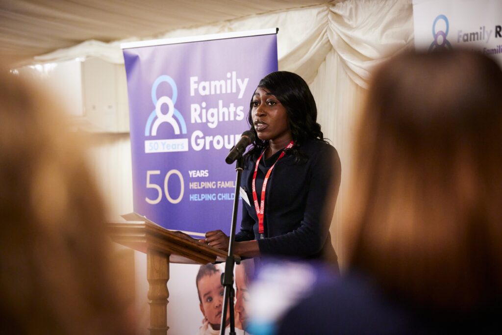 Shanayd Warren speaking at the podium in front of a Family Rights Group 50 years banner