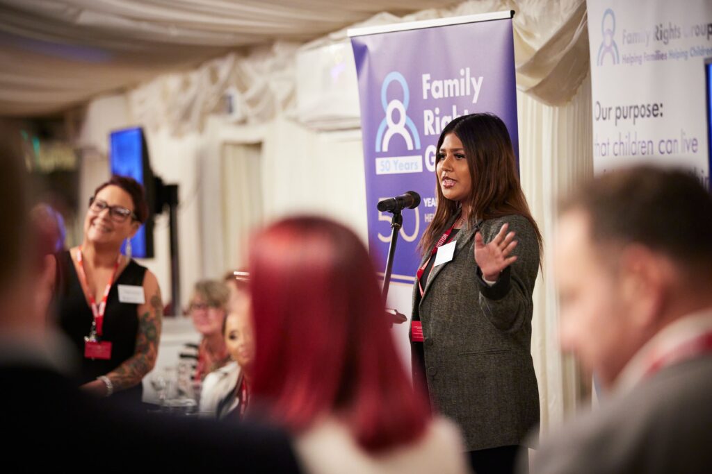 Salma Begum, a care experienced young person, speaking at the podium in front of a Family Rights Group banner